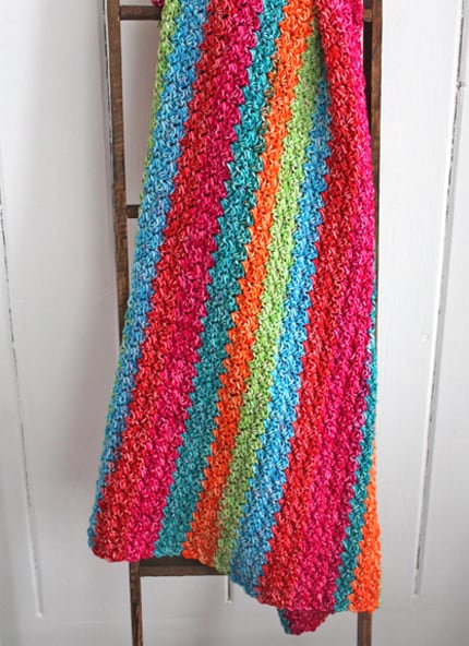 Try this easy Suzette Rainbow Baby Blanket Crochet Pattern. This colorful blanket has a simple 1 row repeat pattern using a self striping yarn. amorecraftylife.com