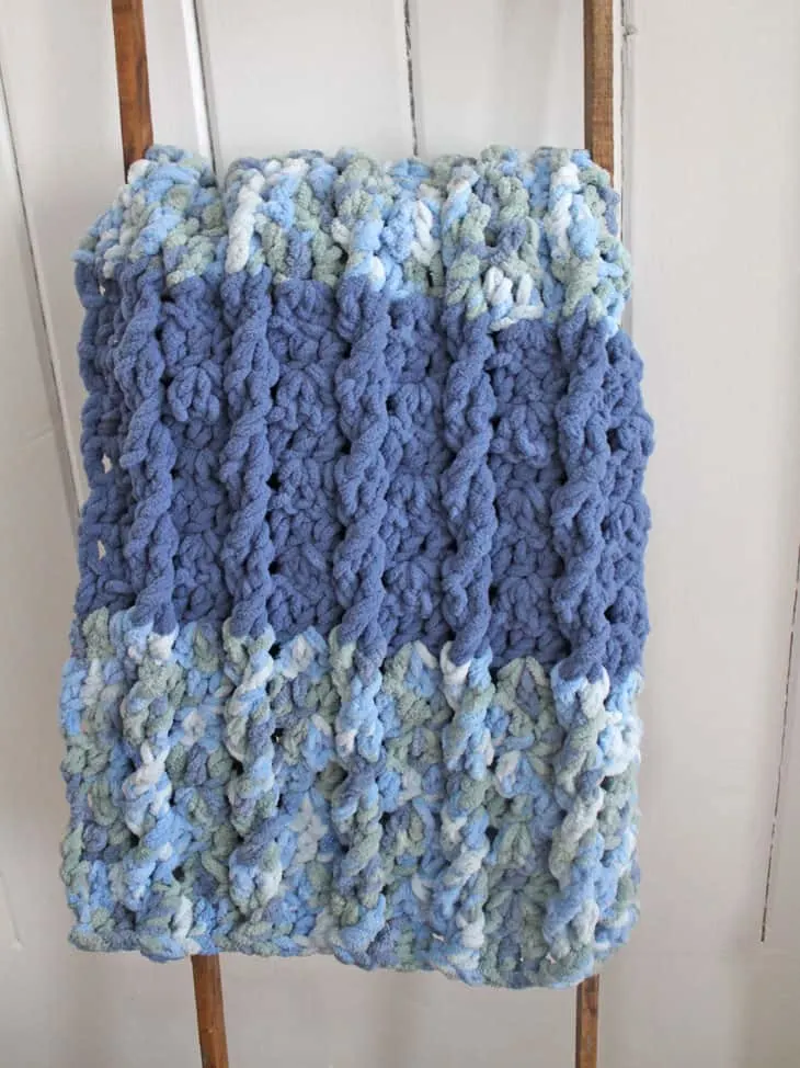 Make this twisted lines crochet blanket pattern. This free pattern uses basic stitches to make this cable design using  Bernat Blanket Yarn.