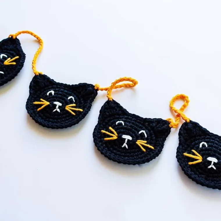 Make a fun black cat garland for Halloween with this free crochet pattern.