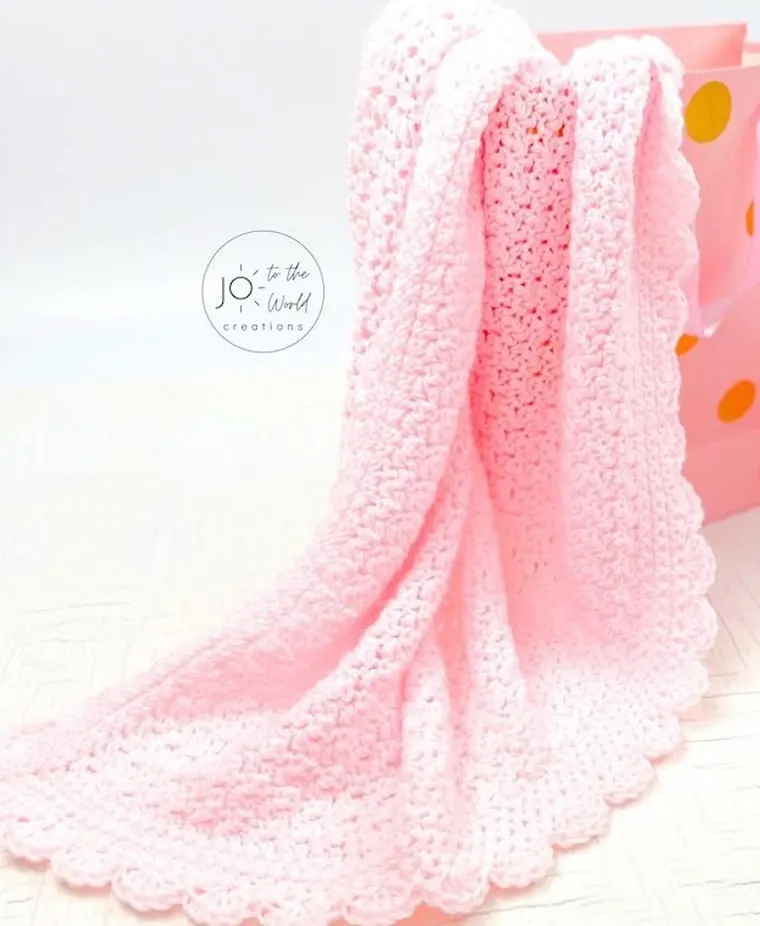 Simple crocheted pink baby blanket with scallop border