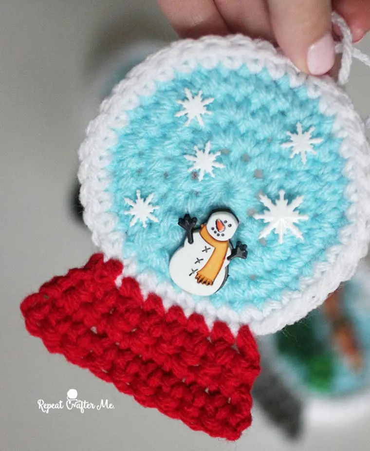 crochet snowglobe ornament with a cute snowman  and snowflake buttons